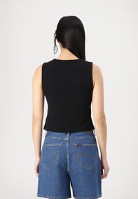 Black sleeveless crop top made of smooth fabric, paired with high-waisted blue denim shorts featuring back pockets and stitching details.