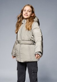 Világosszürke puffdzseki kapucnival, cipzáros záródással és "Calvin Klein" feliratos övvel. Texturált anyag és széles, párnázott ujjak.