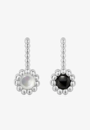 Sølvøreringe i blomsterform med en hvid perleagtig perle på den ene og en sort perle på den anden, samt perle-lignende detaljer på kanterne.