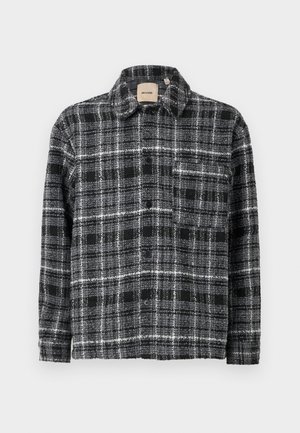 Plaid shirt in black, white, and gray with a collar, long sleeves, and button front. Features a chest pocket for additional detail.