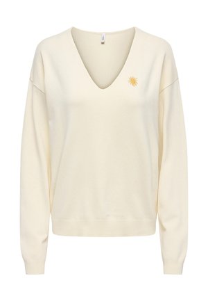 Pull à manches longues couleur crème avec col en V et une petite broderie de soleil jaune sur le côté gauche de la poitrine.