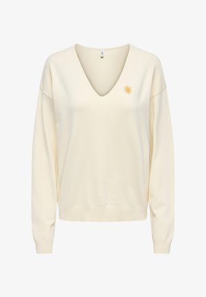 Pull à manches longues couleur crème avec col en V et une petite broderie de soleil jaune sur le côté gauche de la poitrine.