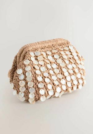 Borsa in paglia beige intrecciata decorata con accenti di conchiglie bianche a forma circolare, caratterizzata da una forma arrotondata e una superficie testurizzata.