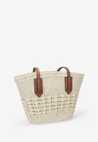 Bolso de playa de paja trenzada en color crema, con dos asas de cuero marrón y un diseño texturizado con una base más ancha y parte superior abierta.