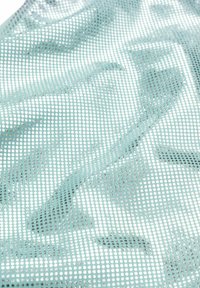 Tessuto in rete azzurro chiaro con un motivo di fori perforati e sottili forme astratte, con una texture liscia e una superficie uniforme.