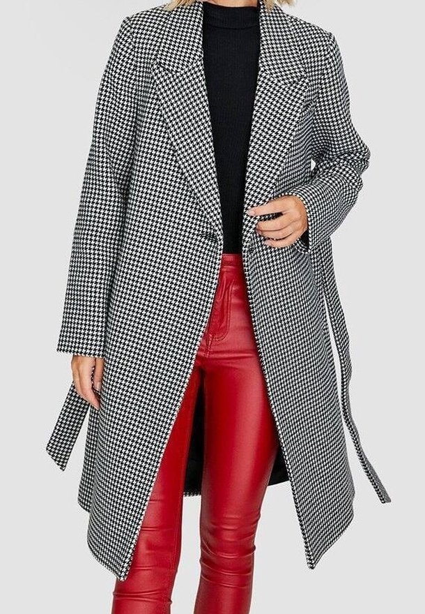 Zwart-wit houndstooth-gepatenteerd overjas met een getailleerde pasvorm, grote revers en een soepele textuur, gecombineerd met rode neplederen broek.