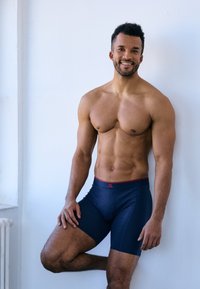 Pánské tmavě modré boxerky s červeným pasem, vyrobené z hladké látky, těsně přiléhající k tělu, s logem na pásku.