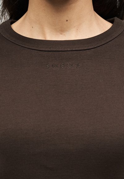 Καφέ ριγέ μπλουζάκι με στρογγυλή λαιμόκοψη και διακριτικό υφασμάτινο σχέδιο, με τη λέξη "soguf" κεντημένη με κλωστή στο ίδιο χρώμα.