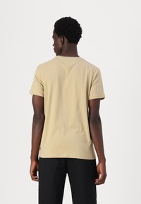 Beige short-sleeve t-shirt in cotton fabric with a crew neck; features a relaxed fit and stitched detailing at the shoulders and hem.