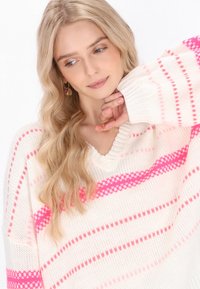 Maglione bianco lavorato a maglia con audaci strisce rosa e scollatura a V. Il tessuto ha una consistenza morbida con polsini a coste.