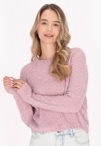 Pulover texturat de culoare violet deschis, cu mâneci lungi și guler zimțat. Croială lejeră cu margini desfăcute la mâneci, asortat cu blugi de denim deschis.