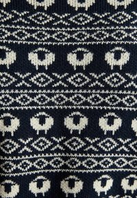 Marineblaue Stricktextilie mit einem cremefarbenen geometrischen Muster aus Schafen und Rauten, das unterschiedliche Formen und Abstände im gesamten Stoff aufweist.