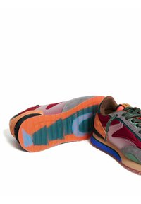Zapatillas multicolores con una mezcla de materiales que incluyen ante, cuero y malla; suela de goma prominente con varios tonos y texturas.