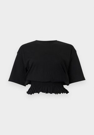 Mustast lühikese varrukaga lühike top laiade varrukatega ja elastse lõngaservaga heletaustal.