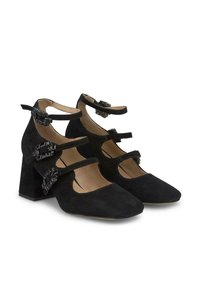 Chaussures noires en daim à talon bloc avec bouts pointus et multiples sangles autour de la cheville. Caractéristiques des accents décoratifs et des découpes sur les côtés.