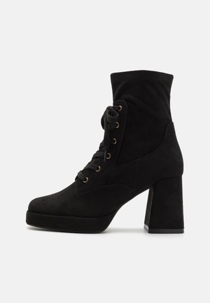 Bottines en daim noir avec un talon bloc haut, lacets à l'avant et œillets dorés ; elles présentent un col ajusté et une texture lisse.