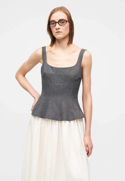 Γκρι τοπ πεπλουμ με τετράγωνη λαιμόκοψη, φαρδιές τιράντες και δομημένες ραφές· συνδυασμένο με μια αέρινη κρεμ φούστα. Λείο ύφασμα.