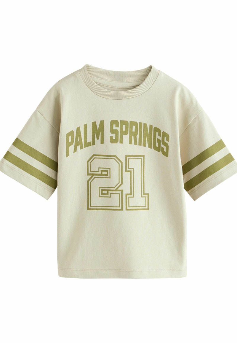 Camiseta de algodón color beige claro con el texto "PALM SPRINGS" y el número "21" en verde oliva. Presenta mangas cortas y acentos a rayas en las mangas.