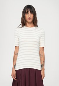 Vaalean beige raidallinen lyhythihainen paita, jossa on pyöreä pääntie. Sileä tekstuuri, vartalonmyötäinen malli, yhdistetty tumman viininpunaisen laskostetun hameen kanssa.