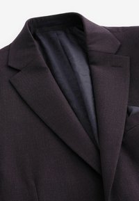 Mørk lilla blazer med tekstureret stof, med en spids krave og et mønstret mørkt foer indeni. Slank pasform med en lomme.