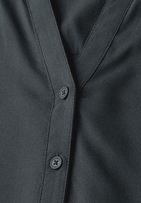 Camicia nera con colletto a v, realizzata in tessuto liscio, con bottoni abbinati e dettagli di cucitura accurati.