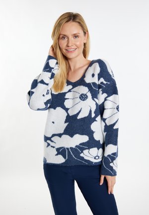Pullovertrui met bloempatroon in marineblauw en wit, met een V-hals, lange mouwen, zachte textuur en een relaxed fit.