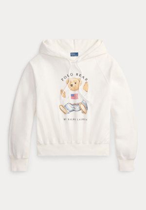 Felpa con cappuccio bianca con un orso che indossa un maglione con la bandiera americana e jeans, testo "Polo Bear by Ralph Lauren" sul davanti.