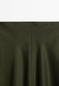Tissu vert foncé avec une couture verticale centrale, présenté sur un fond blanc uni.