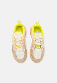 Tenisky s kombinací béžových, bílých a neonově žlutých panelů. Disponují síťovinou, šněrováním v přední části, polstrovaným límcem a texturovanou podrážkou.