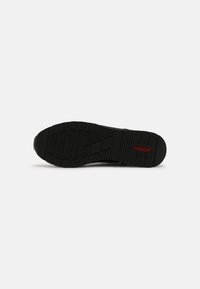 Semelle de chaussure noire avec motif de bande de roulement texturé et logo rouge "rieker" près du talon, vue à plat sur un fond blanc.