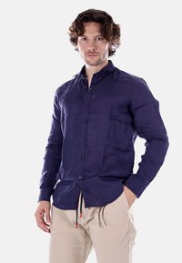 Camicia in lino blu navy con chiusura a bottoni, maniche lunghe e vestibilità casual. Presenta una trama liscia e dettagli di cucitura sottili.