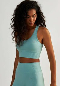 Jasnoniebieski stanik sportowy z teksturowanym wzorem, szerokimi ramiączkami i detalem logo, w połączeniu z pasującymi legginsami o wysokim stanie wykonanymi z tego samego materiału.