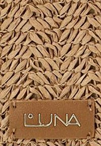 Material de paja trenzada en beige claro con un patrón texturizado. Presenta una etiqueta de cuero marrón con el logotipo "LUNA" estampado en letras metálicas.