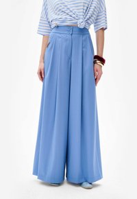Lichtblauwe wijde broek met hoge taille, voorzien van twee voorzakken, twee knopen voor sluiting en een soepele textuur.