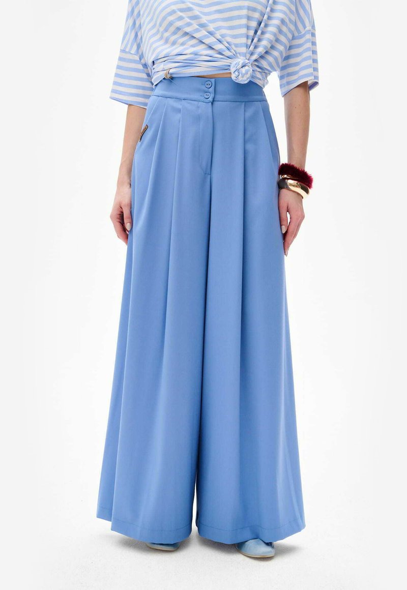 Lichtblauwe wijde broek met hoge taille, voorzien van twee voorzakken, twee knopen voor sluiting en een soepele textuur.