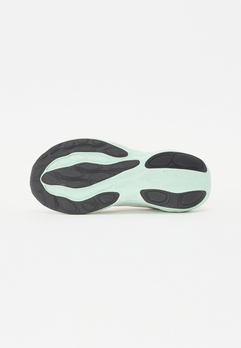 Suela de zapato con una base verde menta y patrones de tracción de goma negra. Forma curvada con materiales texturizados y flexibles y zonas de agarre variadas.