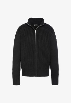 Pull en tricot noir zippé avec un motif texturé en forme de gaufre. Il présente un col montant et des poignets et un ourlet côtelés. Détail de fermeture éclair argentée.