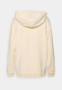 Felpa color crema con cappuccio regolabile, vestibilità comoda, polsini a coste e un design semplice. Tessuto morbido senza loghi o motivi visibili.