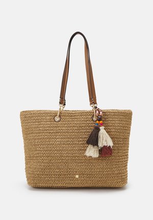 Borsa tote intrecciata color cuoio con manici in pelle marrone e ciondoli a nappina colorati con perline appesi vicino al manico superiore destro.