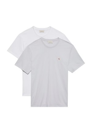 Δύο μοντέρνα T-shirts με στρογγυλή λαιμόκοψη, ένα ανοιχτό γκρι με μικρό λογότυπο Calvin Klein στο στήθος, φορεμένο πάνω από ένα λευκό.