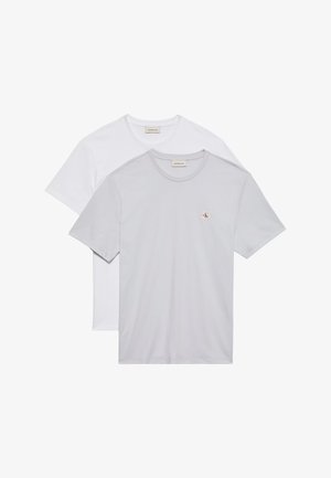 Δύο μοντέρνα T-shirts με στρογγυλή λαιμόκοψη, ένα ανοιχτό γκρι με μικρό λογότυπο Calvin Klein στο στήθος, φορεμένο πάνω από ένα λευκό.