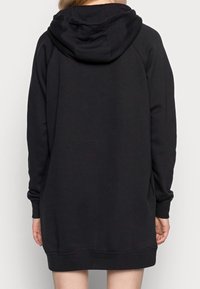 Černé oversized mikinové šaty s prostornou kapucí, dlouhými rukávy a žebrovanými manžetami, vyrobené z měkké a hladké látky. Jednoduchý a jednolitý design.