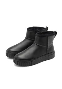 Botas de tobillo de cuero negro con superficie lisa, que cuentan con una suela de goma baja y acentos cosidos. Incluyen tiradores para facilitar su uso.