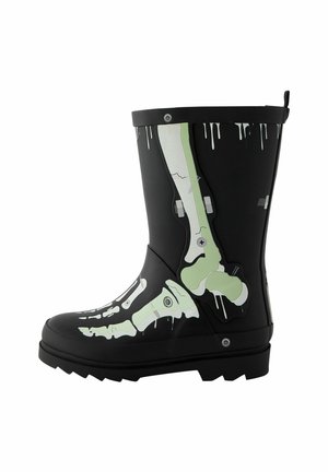 Botte en caoutchouc noire avec des os verts et blancs de style radiographie imprimés le long du côté et des détails de gouttes de peinture blanche sur le bord supérieur.
