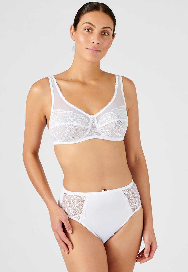 Soutien-gorge en dentelle blanche avec un panneau transparent et des bretelles réglables, associé à une culotte blanche taille haute ornée de détails en dentelle sur les côtés et d'un nœud.