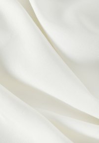 White woven fabric with a smooth texture, featuring subtle variations in thickness and rippling folds, creating a soft, flowing appearance.