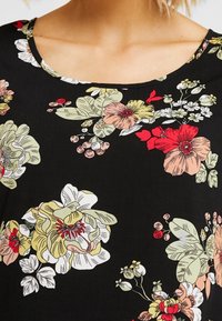 Svart blommig topp med rosa, gula och röda blommor samt gröna löv. Rund halsringning och mjukt tyg med en slät textur.