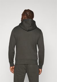 Donkergrijze hoodie met een grote capuchon, lange mouwen en kangoeroe pockets. Gemaakt van zachte stof met een licht gestructureerde afwerking.
