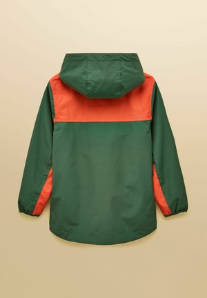 Zelená a oranžová pršiplášťová bunda s kapucňou a elastickými manžetami, zobrazená zozadu na béžovom pozadí.