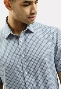 Koszula z krótkim rękawem, zapinana na guziki, w niebiesko-białą kratę, z klasycznym kołnierzykiem i teksturowanym materiałem. Widoczne są dwa guziki.